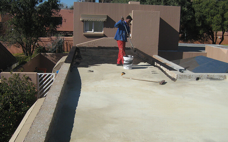 Professional torch-on waterproofing installation on flat concrete roof